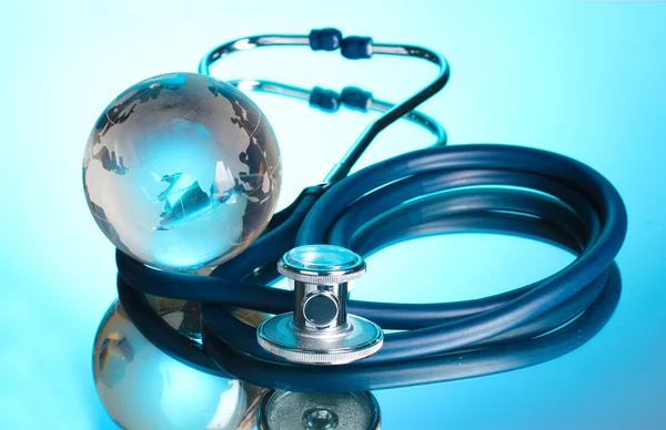 Globe and stethoscope on blue Royalty Free Stock Images