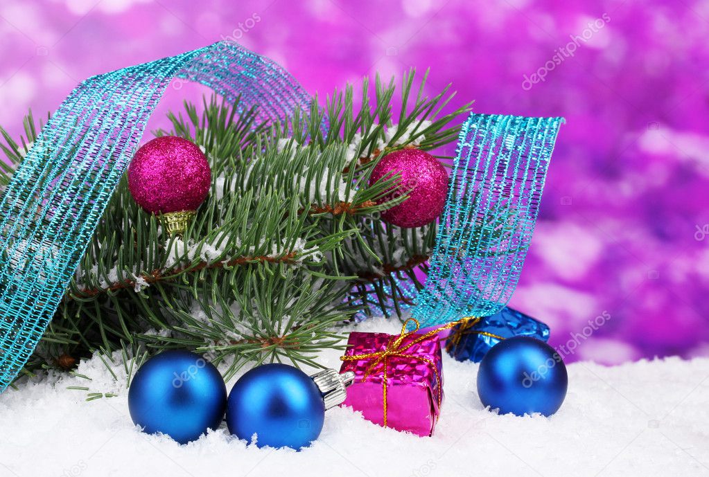 Green Christmas tree with toy and ribbon in the snow on purple