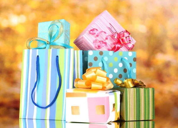 Bright gift bags and gifts on yellow background — Stock Photo, Image
