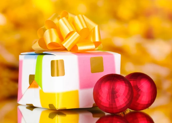 Christmas balls and gift on yellow background — Stock Photo, Image