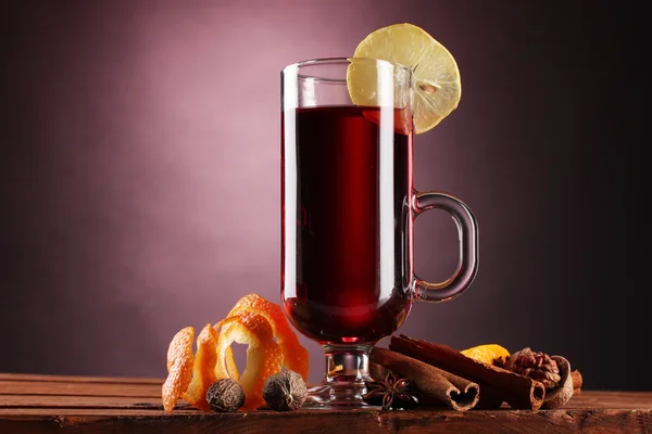 stock image Mulled wine in the glass, spice and lemon on purple background