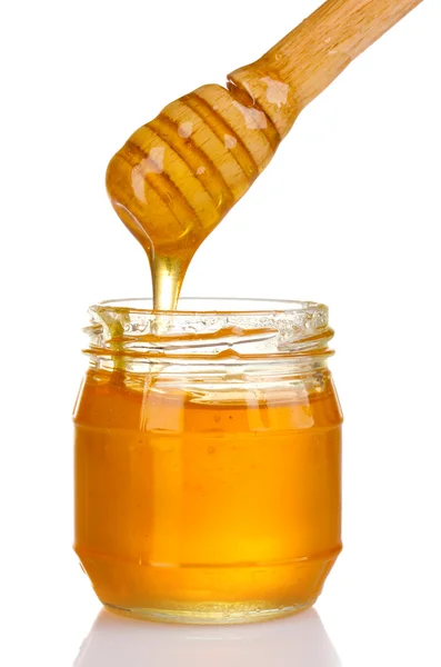 Sklenice medu a dřevěné mrholení izolované na bílém — Stock fotografie