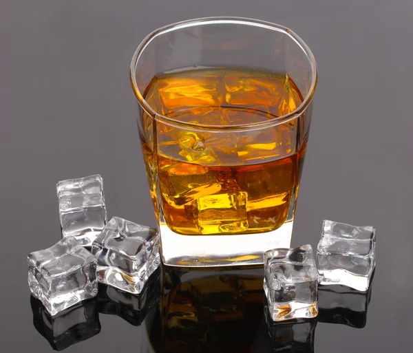Glass of scotch whiskey and ice on grey table — Stock Photo, Image