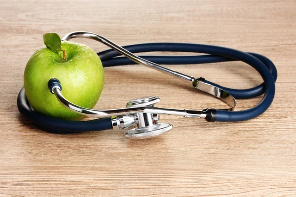 Stéthoscope médical et pomme verte sur fond en bois — Photo