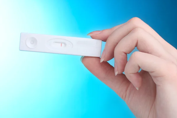 Test di gravidanza in mano su sfondo blu — Foto Stock