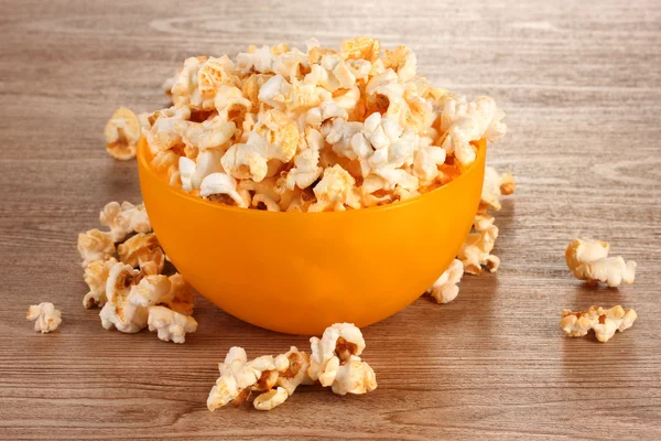 Popcorn i ljusa plast skål på träbord — Stockfoto