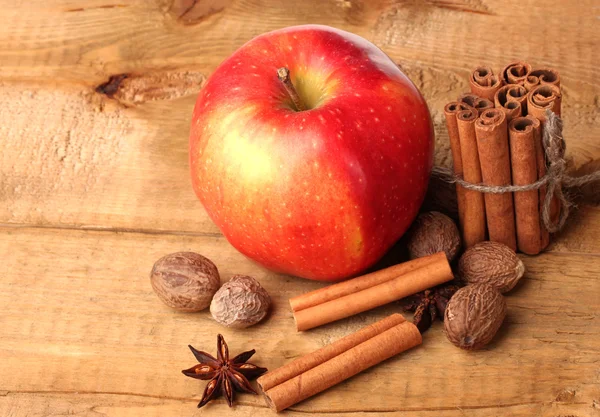 Zimtstangen, roter Apfel, Muskatnuss und Anis auf Holztisch — Stockfoto