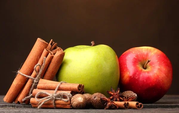 Varas de canela, maçãs noz-moscada e anis na mesa de madeira no fundo marrom — Fotografia de Stock
