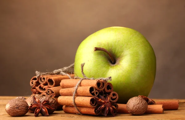 Bâtonnets de cannelle, pomme verte, muscade et anis sur table en bois sur bac brun — Photo