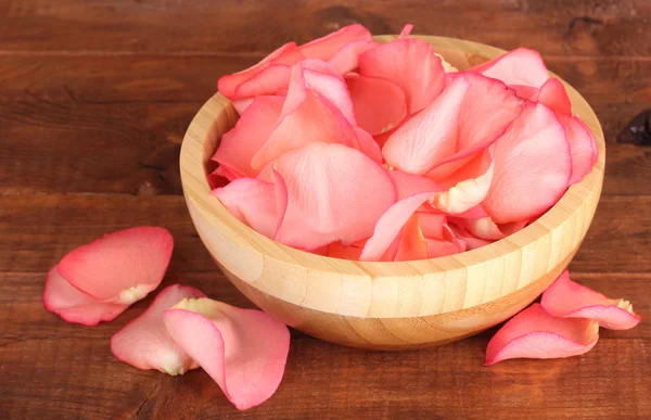 Hermosa rosa pétalos en cuenco de madera en la mesa — Foto de Stock