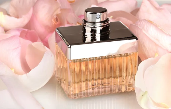Perfume en una hermosa botella y pétalos de primer plano — Foto de Stock