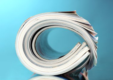 Rolled up magazines on blue background clipart