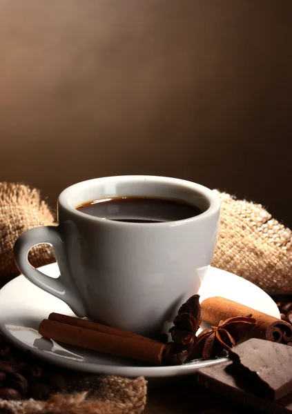 Tasse à café et haricots, bâtonnets de cannelle, noix et chocolat sur table en bois o — Photo