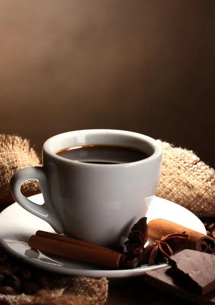 Coffee cup and beans, cinnamon sticks, nuts and chocolate on wooden table o — Stock Photo, Image