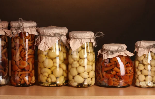 Köstliche marinierte Pilze in den Glasgläsern im Holzregal — Stockfoto
