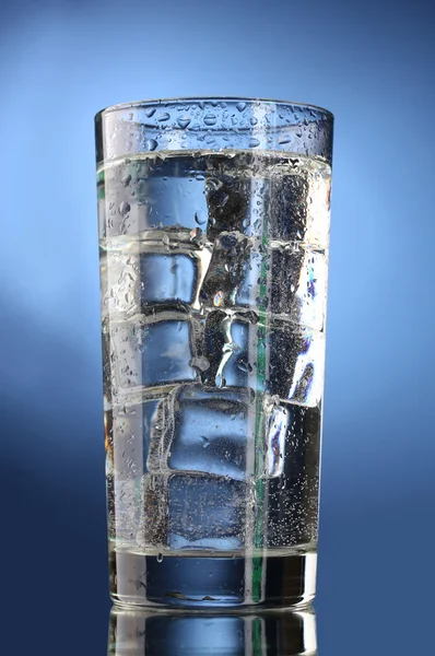 Glass of water with ice on blue background — Stock Photo, Image