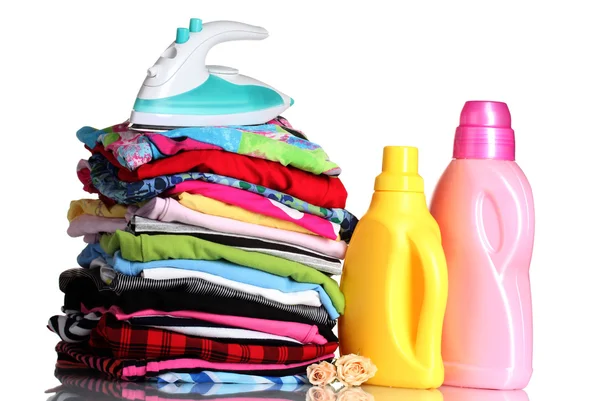 Mucchio di vestiti colorati e ferro da stiro elettrico con detergente isolato su bianco — Foto Stock