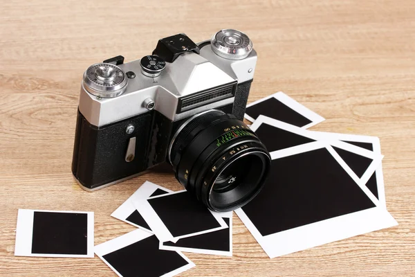 Vieil appareil photo avec papiers photo sur fond en bois — Photo