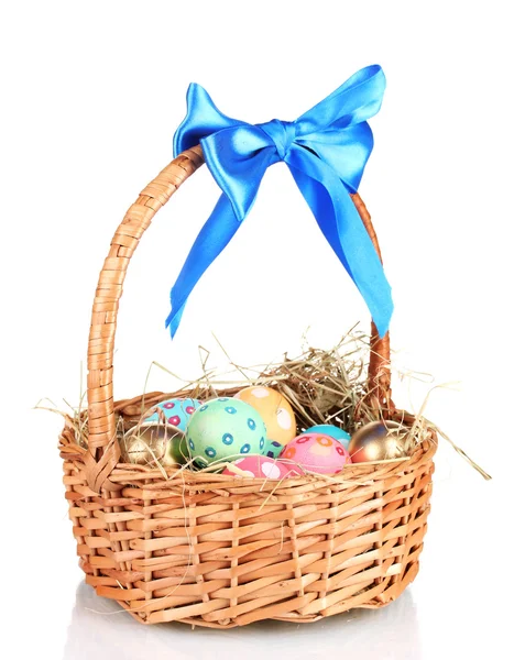 Barevné velikonoční vejce v košíku s modrým lukem izolovaných na bílém — Stock fotografie