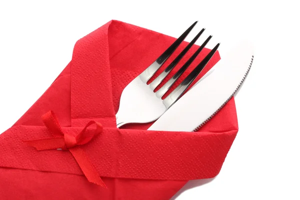 Garfo e faca em um pano vermelho com um arco isolado em branco — Fotografia de Stock