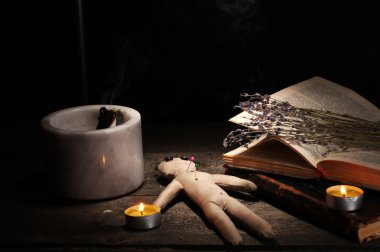 Voodoo doll boy on a wooden table in the candlelight clipart