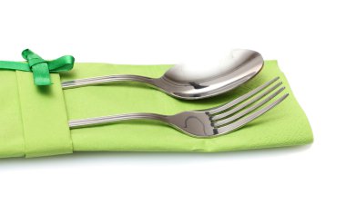 Fork and spoon in a green cloth with a bow isolated on white