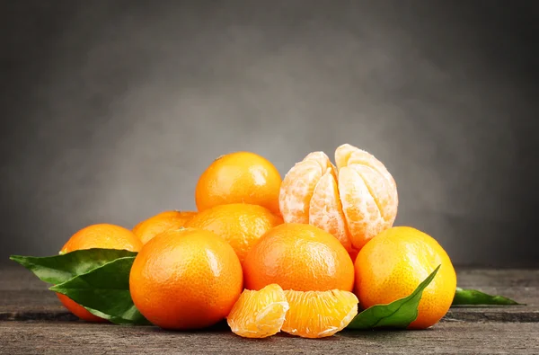 Tangeriner med blad på träbord på grå bakgrund — Stockfoto
