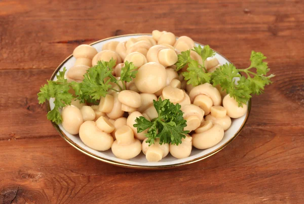 Funghi marinati in piattino su tavolo di legno — Foto Stock