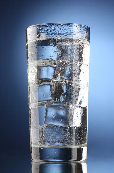 Vidro de água com gelo no fundo azul — Fotografia de Stock