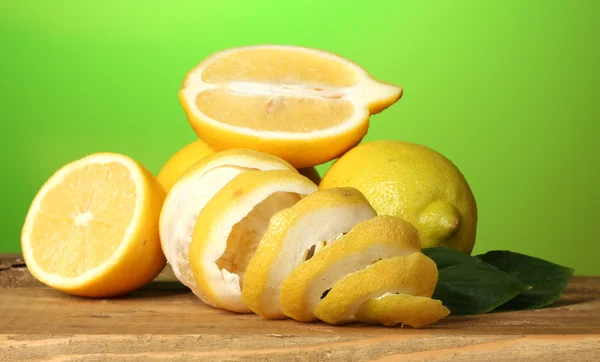 Ripe lemons with leaves on wooden table on green background — Stock Photo, Image