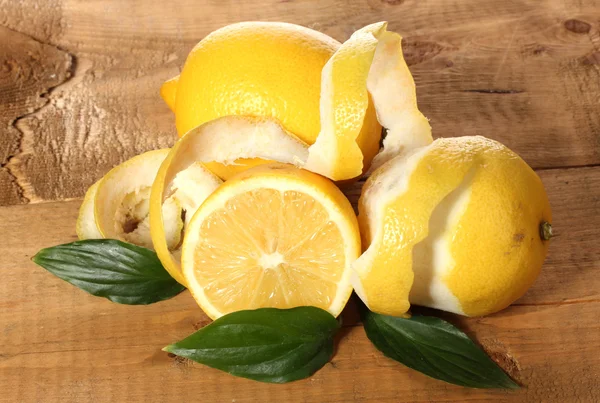 stock image Ripe lemons with leaves on wooden table