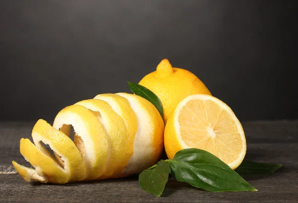 Rijp citroenen met bladeren op houten tafel op grijze achtergrond — Stockfoto