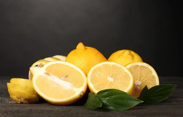 Limoni maturi con foglie su tavola di legno su fondo grigio — Foto Stock