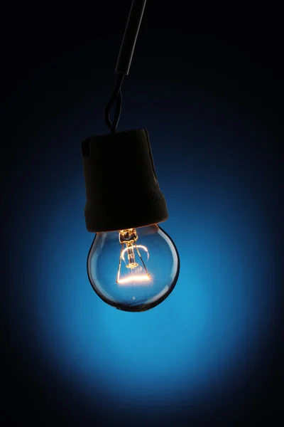 A lit light bulb on blue background — Zdjęcie stockowe