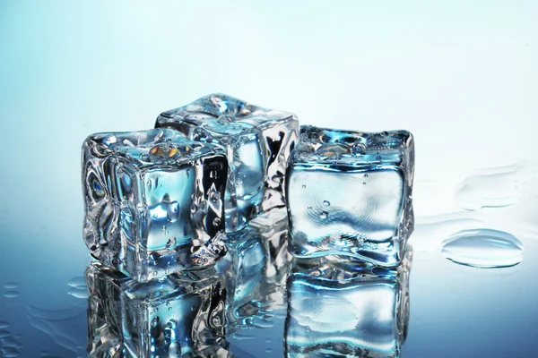 Таяние кубиков льда на синем фоне — стоковое фото