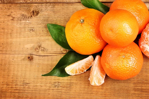 Tangerines with leaves on wooden table — Stock Photo, Image