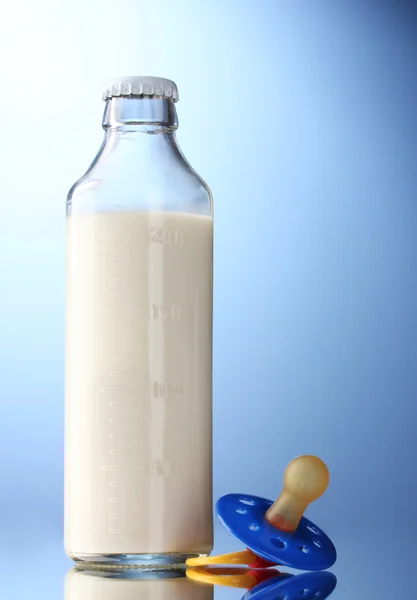 Fles melk en fopspeen op blauwe achtergrond — Stockfoto