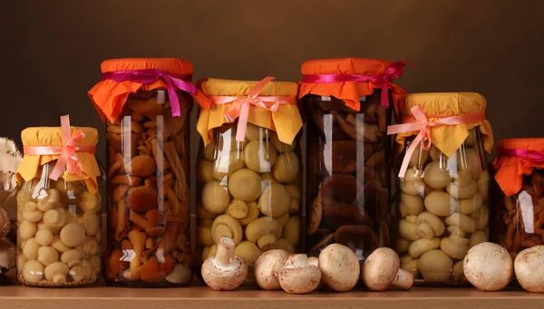 Delicious marinated mushrooms in the glass jars and raw champignons mushroo — Stock Photo, Image
