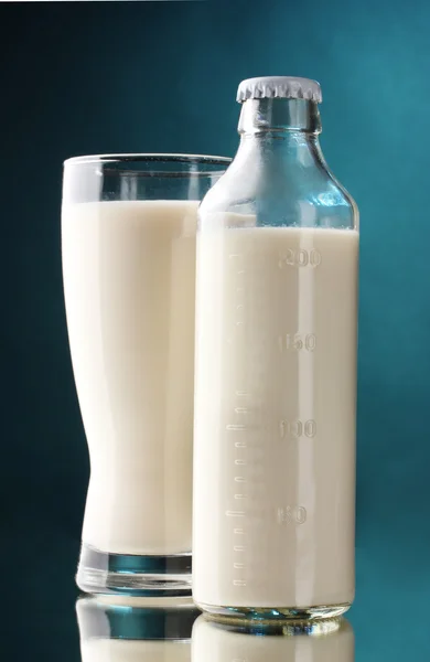 Flasche und Glas Milch auf blauem Hintergrund — Stockfoto