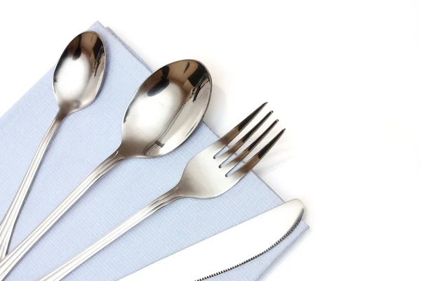 Forchetta, cucchiaio e coltello in un panno blu isolato su bianco — Foto Stock