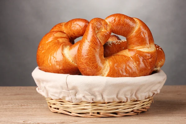 Pan horneado en cesta sobre mesa de madera sobre fondo gris —  Fotos de Stock