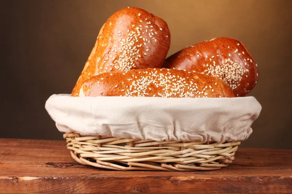 Pane al forno in cesto su tavolo di legno su sfondo marrone — Foto Stock