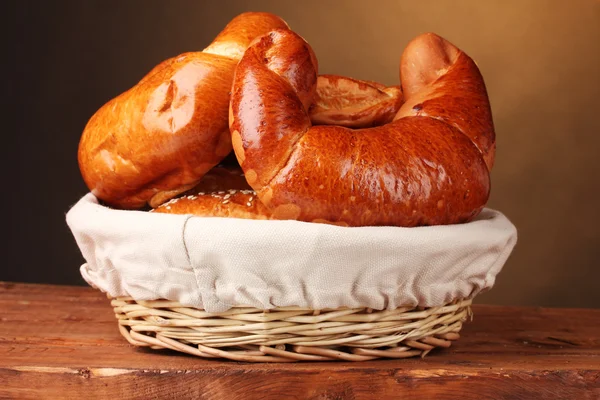 Pečený chleba v koši na dřevěný stůl na hnědé pozadí — Stock fotografie