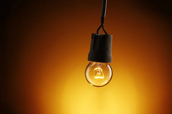 黄色の背景に点灯している電球 — ストック写真