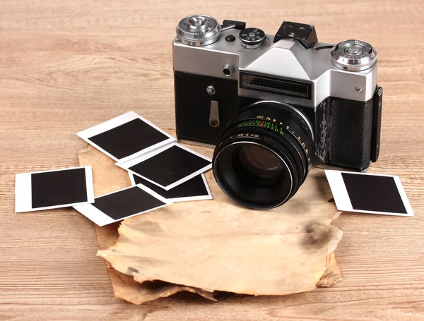 Стара фотокамера з фотопаперами на дерев'яному фоні — стокове фото