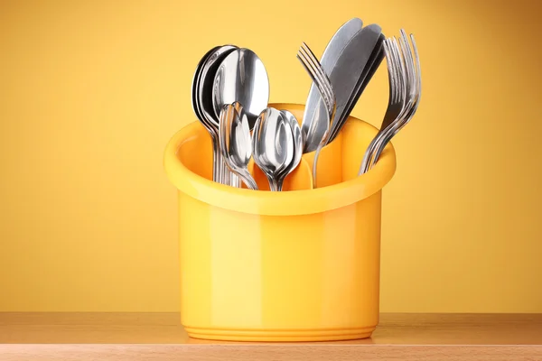 Kitchen cutlery, knives, forks and spoons in yellow stand on yellow backgro — Stock Photo, Image