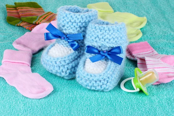 Azul baby booties, meias e chupeta no fundo azul — Fotografia de Stock