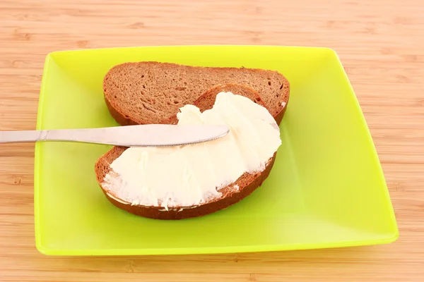 Cuchillo y un pan con mantequilla en el plato — Foto de Stock