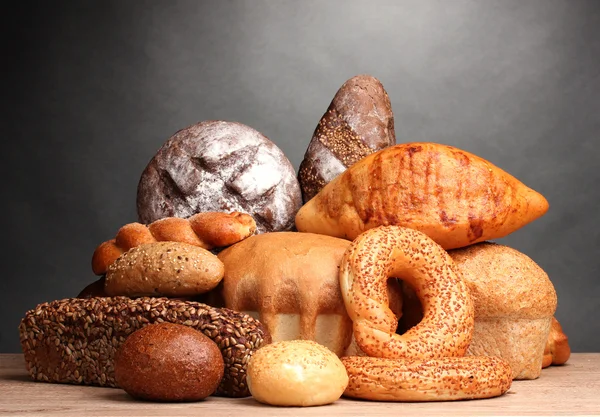 Вкусный хлеб на деревянном столе на сером фоне — стоковое фото