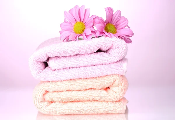 Towels and beautiful flowers on pink background — Stock Photo, Image